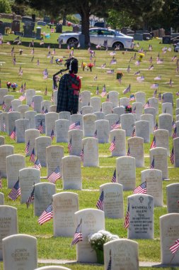 Anma Günü 'nde askeri mezar taşları arasında gayda çalan kişi