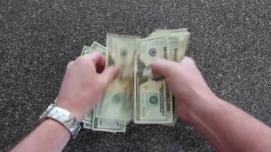 Hand counting twenty-dollar bills