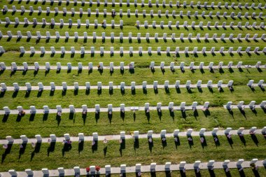 Aerial looking down on military headstones honoring armed forces servicemen decorated with American flags for Memorial Day