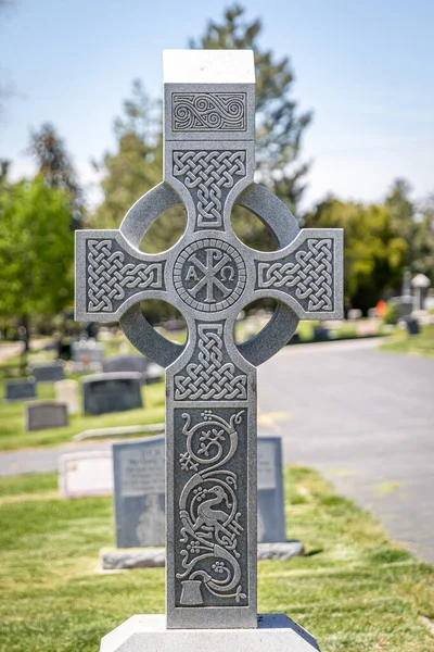 A large Celtic religious cross-shaped headstone at a cemetery in the day