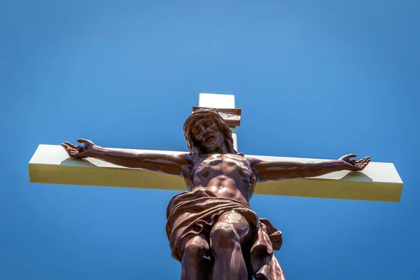 Gold colored statue at a cemetery of Jesus Christ hanging on the cross