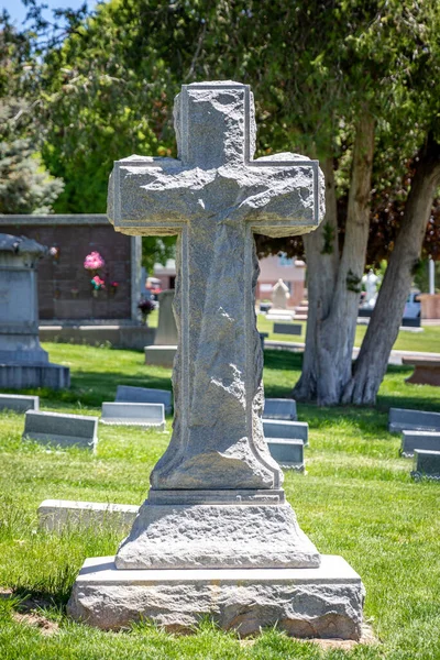 A large religious cross-shaped stone headstone at a cemetery