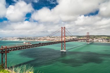 Lisboa, Portugal. April 9, 2022: 25 de April Bridge with a view of the Tagus River and blue sky.