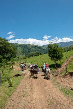 Tamesis, Antioquia, Kolombiya. 1 Temmuz 2018: Bir grup insan gökyüzü ile birlikte ata ve dağa biniyor.
