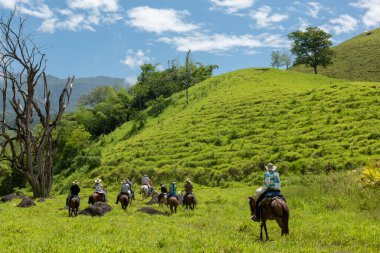 Tamesis, Antioquia, Kolombiya. 1 Temmuz 2018: Bir grup insan gökyüzü ile birlikte ata ve dağa biniyor.