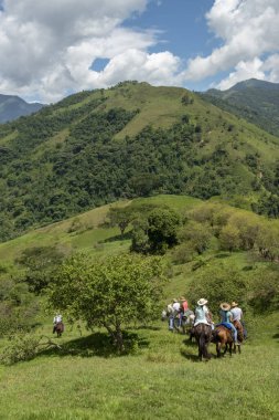 Tamesis, Antioquia, Kolombiya. 1 Temmuz 2018: Bir grup insan gökyüzü ile birlikte ata ve dağa biniyor.