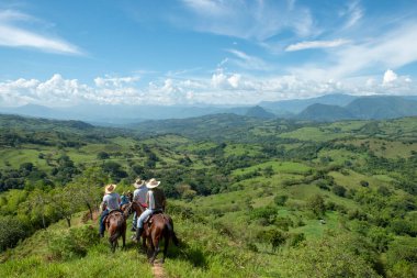 Tamesis, Antioquia, Kolombiya. 1 Temmuz 2018: Mavi gökyüzü ve dağlarla birlikte manzara. İnsanlar ata biniyor..