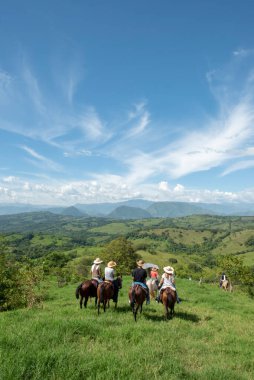 Tamesis, Antioquia, Kolombiya. 1 Temmuz 2018: Mavi gökyüzü ve dağlarla birlikte manzara. İnsanlar ata biniyor..