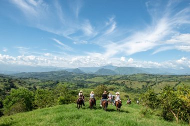 Tamesis, Antioquia, Kolombiya. 1 Temmuz 2018: Mavi gökyüzü ve dağlarla birlikte manzara. İnsanlar ata biniyor..