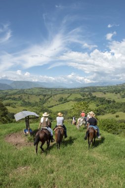 Tamesis, Antioquia, Kolombiya. 1 Temmuz 2018: Mavi gökyüzü ve dağlarla birlikte manzara. İnsanlar ata biniyor..