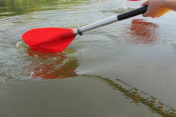 Red paddles for white water rafting and kayaking. Close up of a hand with red paddle kayaking or rafting on the river, concept of spring water sports. Selective focus.