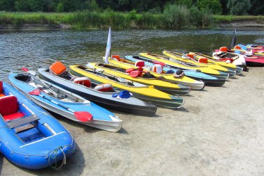 Güneşli bir yaz gününde nehir kıyısında bir kano standı.