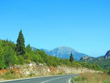 Büyük dağa giden yol. Dağlara giden yol, sola dön. Kenarlardaki işaretleri ve bitki örtüsünü görebilirsiniz. Arka plandaki dağ bir yaz günü görüntüsünde