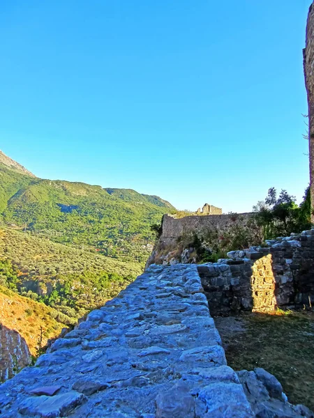 Eski bir kalenin kalıntıları. Dağlarda yeşilliklerle kaplanmış bir Avrupa kalesinin eski kalın taş duvarları. Tahkimatların yıkıntılarında kapılar ve kemerler