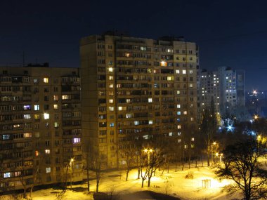 Geceleri apartmanların iç kısımlarında insanlar olan parlak pencereler. Şehirde kış gecesi pencereleri aydınlık olan bir ev..