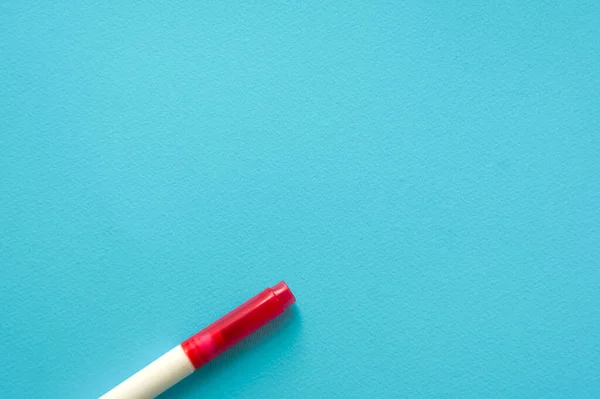 The creative concept of creativity is empty. A single red marker for marking lie off the edge of the blue kraft background. Back to school. Medical Notes. In aquamirin tones.