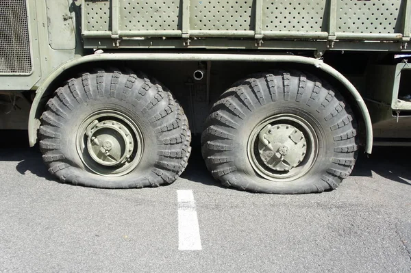 A punctured and flat tire of military equipment of the armored personnel carrier. Military conflict, the shelling of the wheel. Close-up. Punctured tire of a military off-road vehicle
