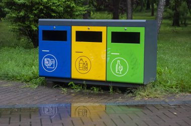 Parktaki çok renkli geri dönüşüm kutuları. Plastik, kağıt ve cam için açık hava çöp kutuları. Sürdürülebilir yaşam tarzı konsepti. Mavi, sarı, yeşil