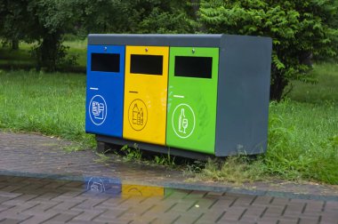 Parktaki çok renkli geri dönüşüm kutuları. Plastik, kağıt ve cam için açık hava çöp kutuları. Sürdürülebilir yaşam tarzı konsepti. Mavi, sarı, yeşil