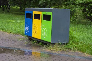 Parktaki çok renkli geri dönüşüm kutuları. Plastik, kağıt ve cam için açık hava çöp kutuları. Sürdürülebilir yaşam tarzı konsepti. Mavi, sarı, yeşil
