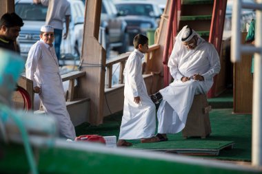 Doha, Katar - 05 Mart 2019: Geleneksel giyimli Katar ailesi eski pazar pazarı Souk Waqif 'te takılıyor.