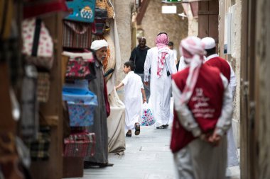Doha, Katar - 05 Mart 2019: Geleneksel giyimli Katar ailesi eski pazar pazarı Souk Waqif 'te takılıyor.