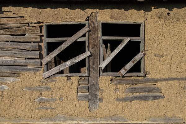 Sunja, Croatia, April 20,2021 : Facade of mud and straw on old wooden house.