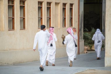 Doha, Katar - 15 Nisan 2022: Geleneksel giyimli Katar yerlileri eski pazar pazarı Souk Waqif 'te takılıyorlar.