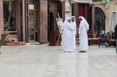 Doha, Katar - 15 Nisan 2022: Geleneksel giyimli Katar yerlileri eski pazar pazarı Souk Waqif 'te takılıyorlar.