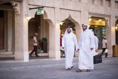 Doha, Katar - 15 Nisan 2022: Geleneksel giyimli Katar yerlileri eski pazar pazarı Souk Waqif 'te takılıyorlar.