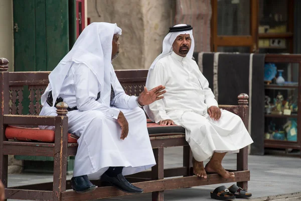 Doha, Katar - 15 Nisan 2022: Geleneksel giyimli Katar yerlileri eski pazar pazarı Souk Waqif 'te takılıyorlar.