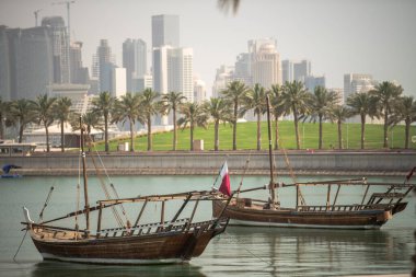 Doha, Katar - 24 Nisan 2022: Arka planda Doha 'nın fütüristik silueti olan geleneksel dhow gemileri.