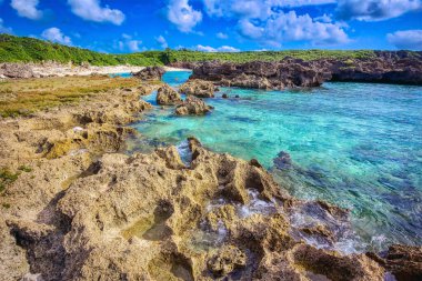 Japonya, Okinawa 'daki Miyakojima, Yaeyama adaları üzerinde turkuaz suyu bulunan Rocky mercan resifi plajı.