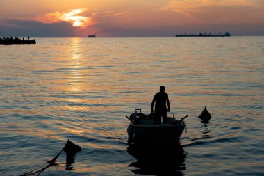 Trieste 'de gün batımında Akdeniz' den dönen teknesinde bir adamın silüetiyle. .