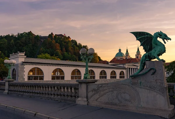 Gün batımında Ljubljana 'daki ejderha köprüsü Kale ve katedral geçmişiyle .