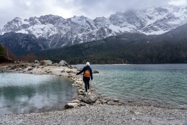 Grainau Almanya 'daki güzel Eibsee dağ gölünde Zugspitze dağları arka planda kaya yolunda yürüyen turist kadın. .