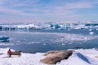 Ilulissat 'ın deniz manzarası ve buzdağları kıyıdaki turist kadın. .