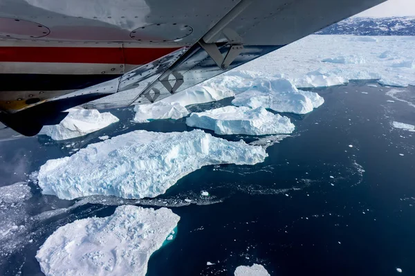 Okyanusta yüzen buzdağlarıyla Grönland üzerinde uçan bir tur.