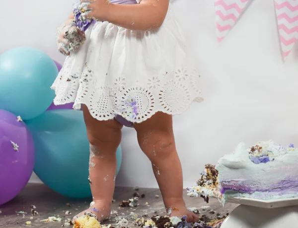 One year cake smash photo shoot with girl in white dress with blue and purple balloons and pink decoration