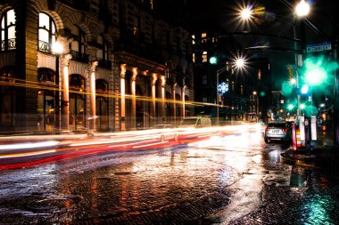 Arabalar ve otobüsler şehir merkezindeki yoğun kavşakta gece yarısı sağanağından sonra hızla ilerliyorlar. 