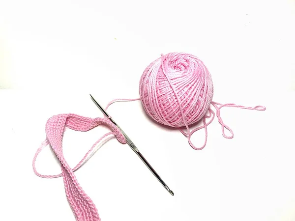 Beyaz arkaplanda pembe ipliğe sahip tığ işi araçları