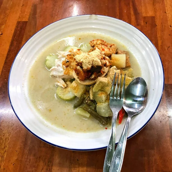 Lontong şapkası Gomeh Endonezya 'da geleneksel bir yemektir. Tahta masadaki bir tabakta servis ediliyor..