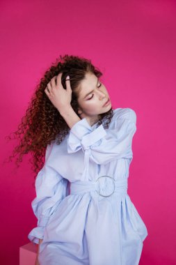 Pembe arka planda dalgalı, parlak, sağlıklı saçları olan manken kız. Parlak makyajlı.