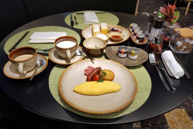 Tam bir kahvaltı. Omlet, sosis, haşhaş, krep, kahve ve süt ile servis edilir. Güne başlamak için harika bir yol. Beppu, Oita, Kyushu, Japonya