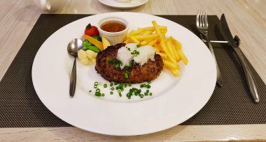 Hamburger bifteği, içi sulu, ızgara lezzet. Patates kızartması ve haşlanmış sebzeyle birlikte geliyor. Doğranmış taze soğanlı garnitür. Fukuoka, Kyushu, Japonya