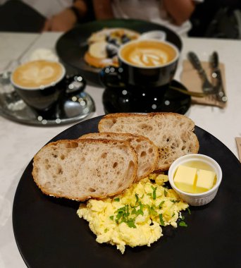 Ciabatta ile sağlıklı bir brunch, çırpılmış yumurta ve tereyağı. Bir fincan latte ile