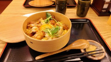 Üstünde çiğ yumurta olan bir kase Japon tavuklu pilav. Yerel taze çiftlik tavuğu. Biraz kişniş, turp dilimleri ve bir fincan sıcak yeşil çay ile garnitür. Ferahlatıcı. Tokyo, Japonya