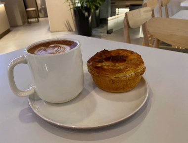 Kahvaltıda taze pişmiş tavuk mantarlı turta ve sıcak çikolata. Kafede rahat bir ortam..