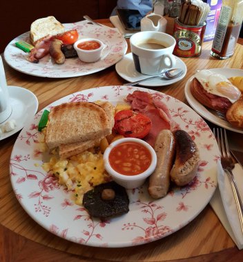 Geleneksel genel kahvaltıda domuz pastırması, sosis, yumurta, fırında fasulye, domates, mantar, tost ve bir fincan kahve yer alır. Londra, İngiltere, Birleşik Krallık.