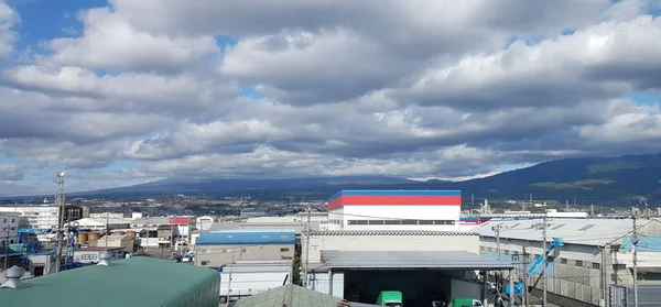 Bir kasaba ve fabrikalardan geçen Hikari Shinkansen 'in görüntüsü. Mavi gökyüzü, dağ, dükkanlar ve fabrikalar manzaralı. Shiga Bölgesi, Japonya.